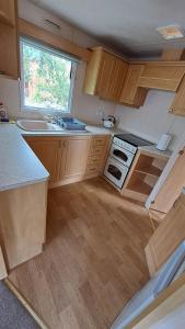 a small kitchen with wooden cabinets and a window at Letniaczki ABI in Rydzewo