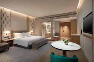 無錫市にあるHoliday Inn Wuxi Central Station, an IHG Hotelのベッドとテーブルが備わるホテルルームです。