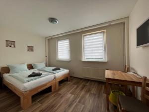 a room with two beds and a table and windows at Apart Pension Plaue in Brandenburg an der Havel