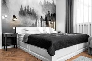 a bedroom with a bed with a forest mural on the wall at Apartamenty Pod Kominkiem in Rydzewo