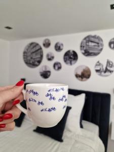 a person holding a coffee cup on a bed at LIEV Amsterdam Cozy boutique suite in The Pijp in Amsterdam