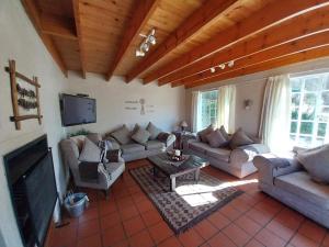 a living room with couches and a flat screen tv at Hillside Cottage in Clarens