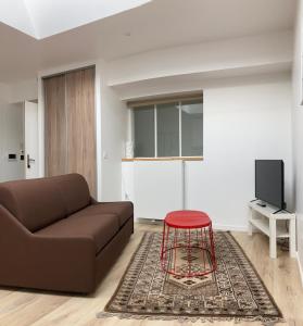 - un salon avec un canapé brun et un tabouret rouge dans l'établissement Lotentik residence, à La Rochelle