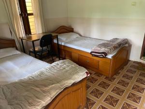 a room with two beds and a table and a desk at Rupa View Guest house in Pokhara