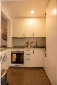 uma cozinha com armários brancos e um lavatório em Cozy Beach Apartment W/ Sea View, Free Parking & AC em Carvoeiro