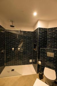 baño con aseo y pared de azulejos negros en Cozy Beach Apartment W/ Sea View, Free Parking & AC en Carvoeiro