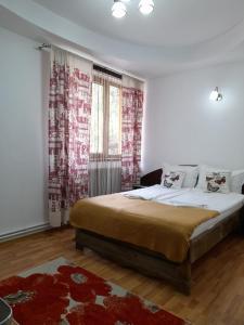 1 dormitorio con 1 cama grande y cortinas rojas y blancas en Pensiunea Gil en Predeal