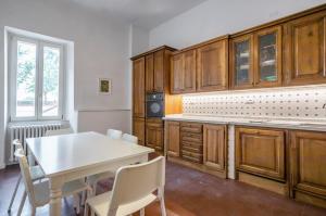 Lucca Historic & Cozy Central Apartment! في لوكّا: مطبخ بدولاب خشبي وطاولة وكراسي بيضاء