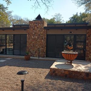 a building with a fire pit in front of it at Woodpecker Villa Guesthouse in Thabazimbi