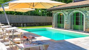 a swimming pool with chairs and an umbrella at Villa Elsa 6, Emma Villas in Filetto