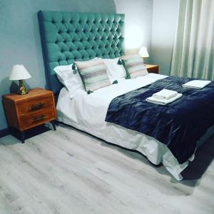 um quarto com uma cama grande e uma cabeceira azul em Woodpecker Villa Guesthouse em Thabazimbi