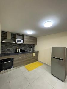 eine Küche mit einem Kühlschrank aus Edelstahl und einem gelben Teppich in der Unterkunft Auae hills lodge in Faaa