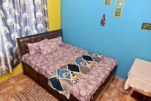 1 dormitorio con 1 cama con edredón morado en Rosa’s Guest House, en Siroda