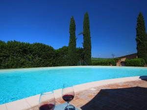 two glasses of wine sitting next to a swimming pool at Attractive Farmhouse in Montalcino with Terrace in San Giovanni dʼAsso