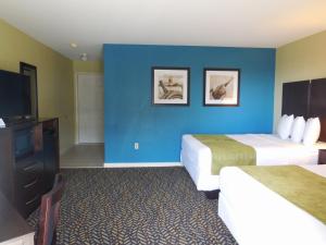 a hotel room with two beds and a flat screen tv at Anchor Inn in Chincoteague