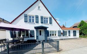 ein weißes Haus mit einem Zaun und einem Tisch in der Unterkunft Hochwertiges Fischerhus mit Terrasse und Grill in Greifswald