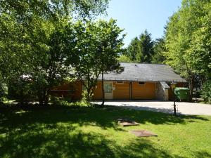 une maison avec un garage et des arbres dans une cour dans l'établissement Comfortable Chalet in Ovifat near Ski Lift, à Waimes
