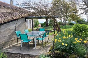 uma mesa e cadeiras num jardim com flores em Les Glycines em Saint-Pierre-de-Buzet