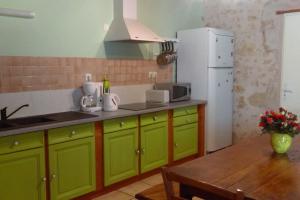 cocina con armarios verdes y nevera blanca en Les Glycines, en Saint-Pierre-de-Buzet