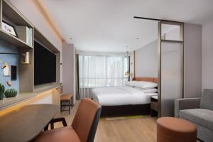 a hotel room with a bed and a couch and a table at Home2 Suites by Hilton Beijing West Station in Beijing