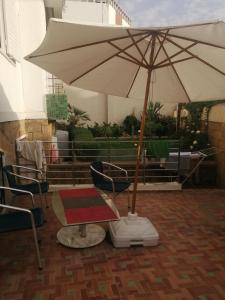 un parasol blanc, deux chaises et une table dans l'établissement Miramar, à Harhoura