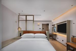 a bedroom with a large white bed and a flat screen tv at Home2 Suites by Hilton Beijing West Station in Beijing