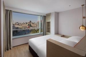 a hotel room with a bed and a large window at Home2 Suites by Hilton Beijing West Station in Beijing
