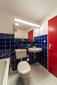 La salle de bains est pourvue de toilettes, d'un lavabo et d'une porte rouge. dans l'établissement Chesa Chatrigna - Celerina - apartment up to 5 people, à Celerina