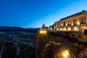 een gebouw aan de zijkant van een berg 's nachts bij Parador de Ronda in Ronda