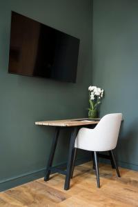 a table with a white chair and a tv on a wall at Hotel des Brasseurs in De Haan