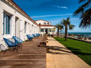 La Villa Saint Jean في لي سابلِ دولونْ: صف من الكراسي الزرقاء على ممشى خشبي بالقرب من الشاطئ