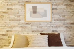 a brick wall with a picture above a bed with pillows at ウーブル博多504 in Sumiyoshi