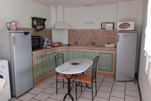 una cocina con armarios verdes y una mesa con sillas en Tamaris en Saint-Pierre-de-Buzet