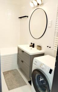uma casa de banho com uma máquina de lavar roupa e um espelho. em Forest Hill apartment em Budapeste