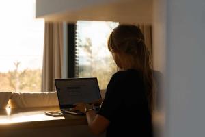 une femme assise à une table avec un ordinateur portable dans l'établissement Exclusive off-grid tiny home at the beach - Kenshó, 