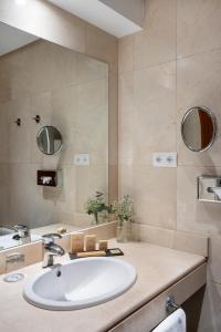 ein Badezimmer mit einem Waschbecken und einem großen Spiegel in der Unterkunft Parador de Ronda in Ronda