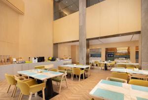 a restaurant with tables and chairs and a kitchen at Home2 Suites by Hilton Beijing West Station in Beijing