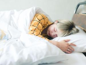 a woman sleeping in a bed with a stuffed animal at Kagan Hotel & Hostel in Kyoto