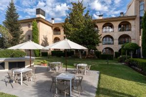 un patio avec des tables et des parasols devant un bâtiment dans l'établissement Parador de Ronda, à Ronda