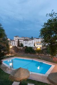 une grande piscine bleue avec parasols et bâtiments dans l'établissement Parador de Ronda, à Ronda