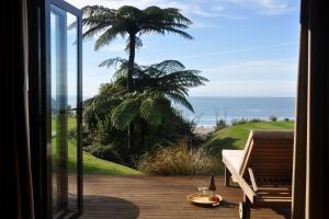a room with a view of the ocean from a porch at Adrift In Golden Bay- Absolute Beachfront Villas in Collingwood