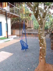 Eine blaue Schaukel hängt von einem Baum im Innenhof in der Unterkunft Nostalgia Homestay in Vythiri