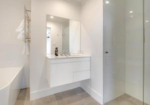 a white bathroom with a sink and a shower at Guthega Inn in Perisher Valley