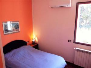 a bedroom with an orange wall with a bed and a window at Relax immersed within the Sette Fratelli Mountains in San Gregorio
