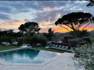 a swimming pool in a yard with a sunset in the background at HomeStay Bormes in Bormes-les-Mimosas