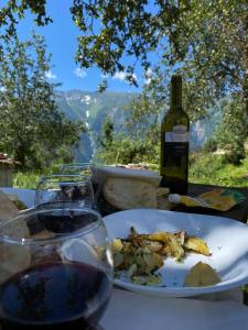 Guest House Eceri في ميستيا: طاولة مع طبق من الطعام وزجاجة من النبيذ