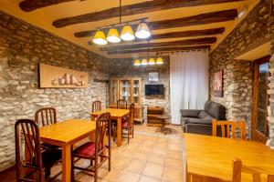 a living room with wooden tables and a stone wall at Rural Jordà in Rodonyà