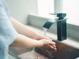 een persoon die zijn handen wast onder een waterkraan bij Kagan Hotel & Hostel in Kyoto