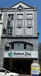 un grande edificio grigio con un cartello di arpione di Hotel Harbour Stay a Malacca