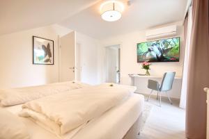 two beds in a white room with a desk at Pension - Ferienwohnungen Zollner in Villach